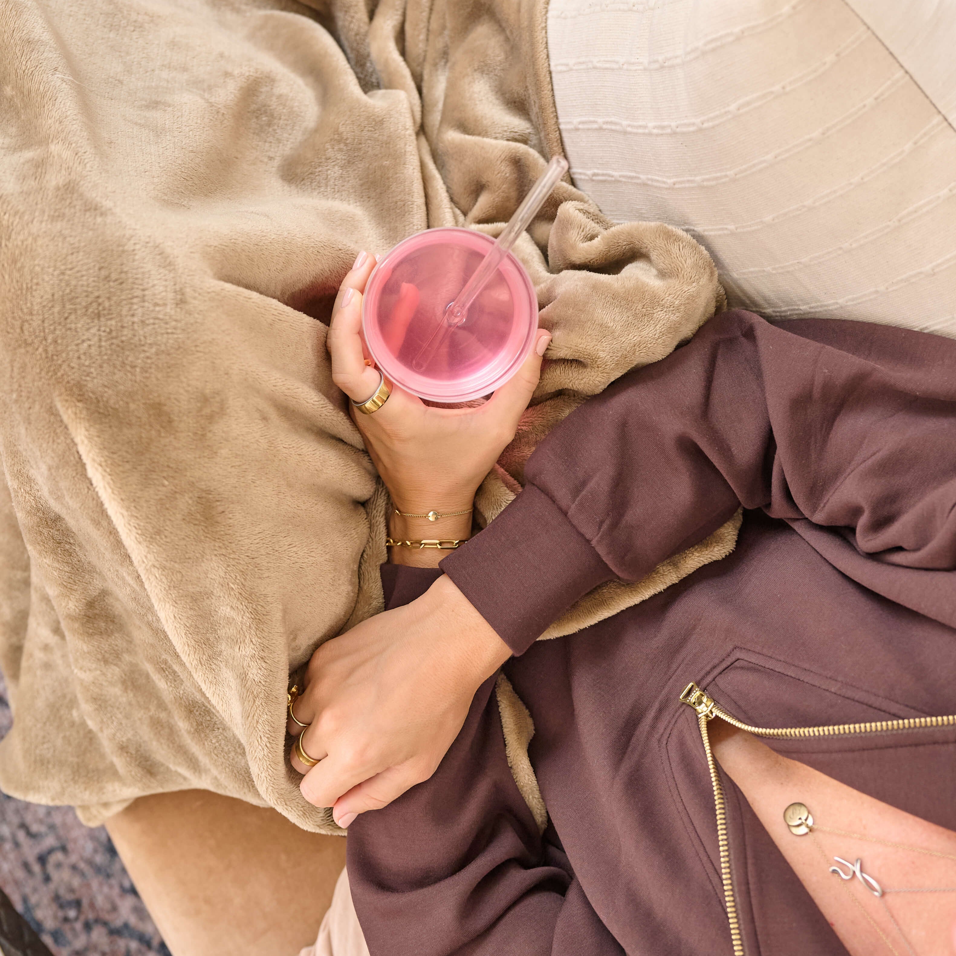 Person holding a glass of mixed berry VitaResiliance under a beige blanket