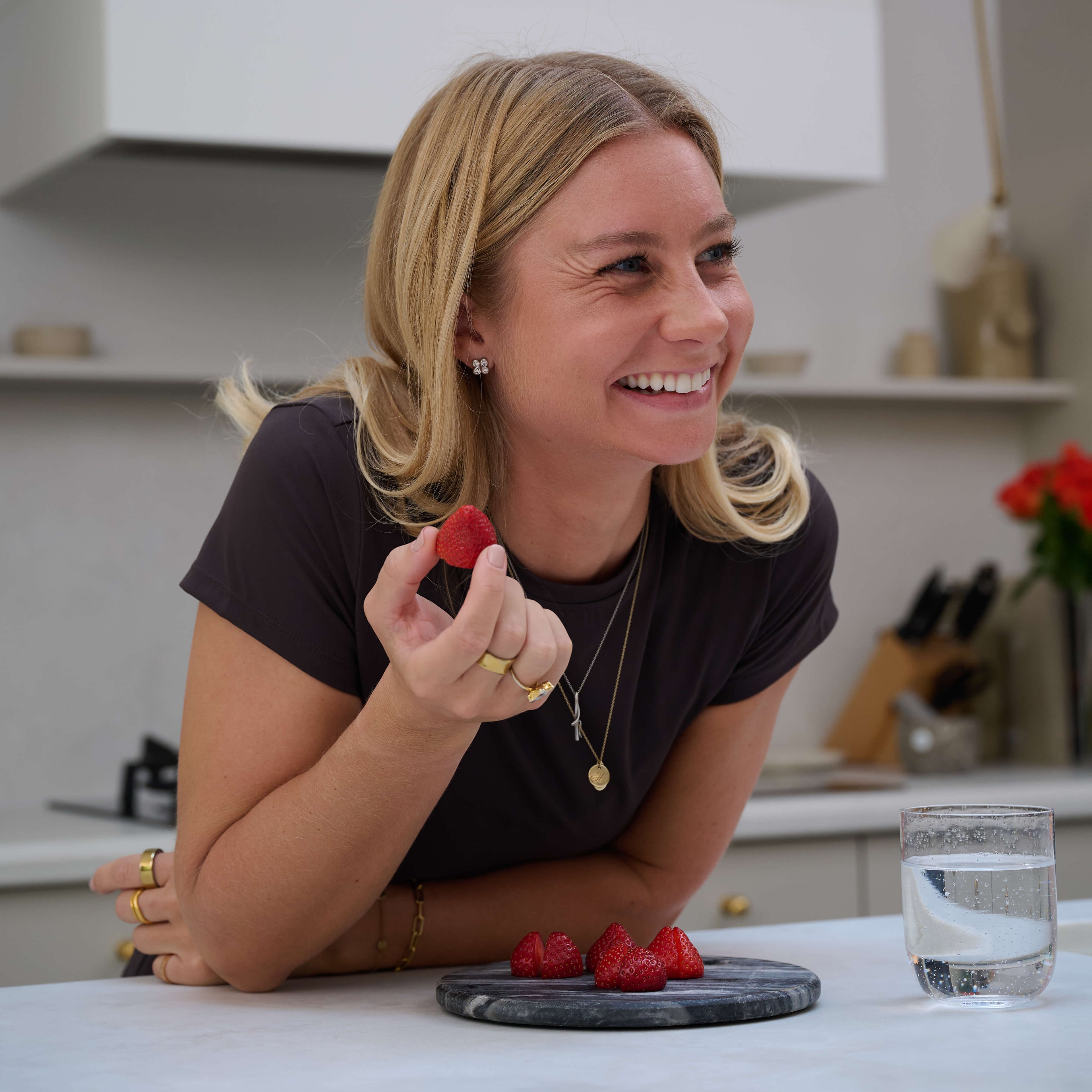 Polly The Founder of Vhyne holding a strawberry in a kitchen setting