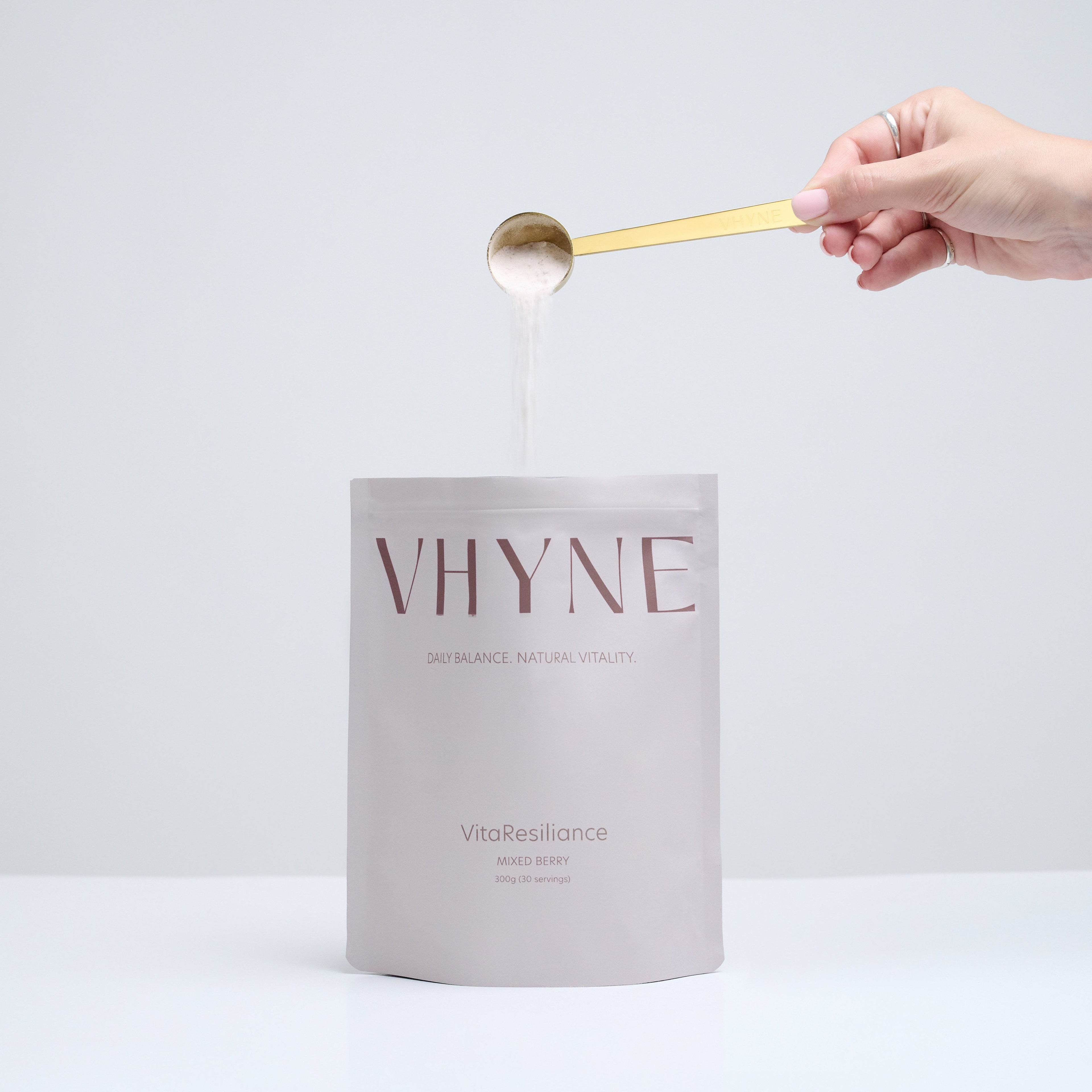 A pouch of VitaResiliance with a hand taking a scoop of powder