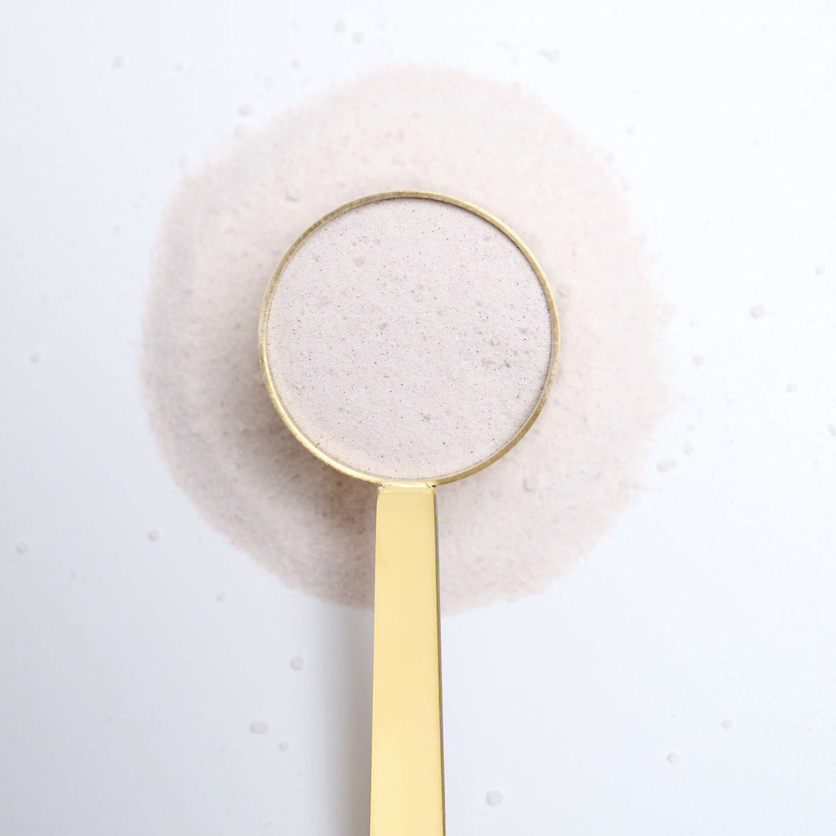 Gold spoon with VitarResiliance powder on a textured white surface